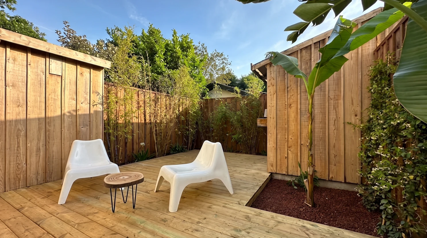 Terrasse extérieure privative avec deck en bois traité autoclave, entourée de clôtures en planches de bois vertical