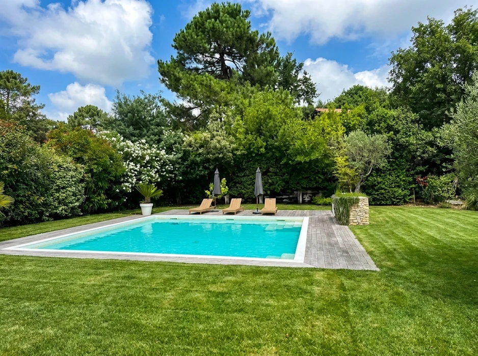 Jardin méditerranéen aménagé avec massifs de lavande, plantes fleuries roses, cyprès élancés et pin parasol